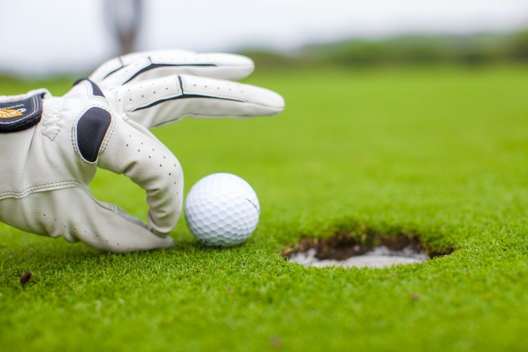 Golf player man pushing golfball into the hole