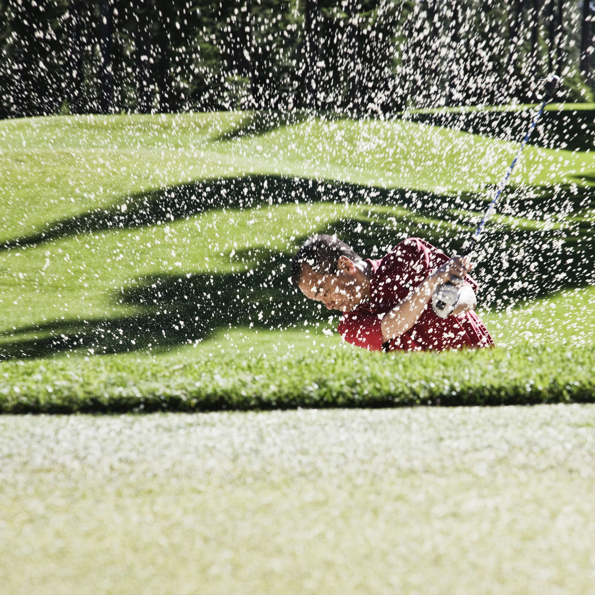 Senior golfer playing out of a bunker on the golf course.